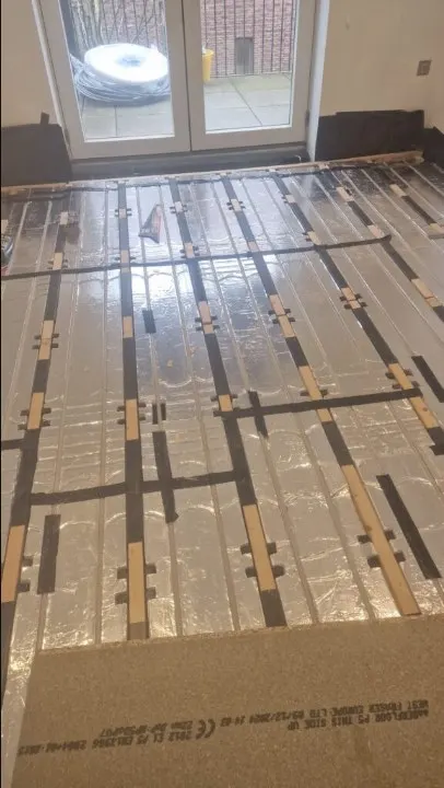 Underfloor heating pipe laid on insulation boards across a room floor
