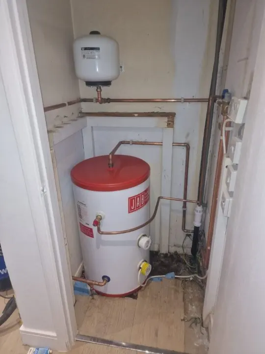 Hot water cylinder and expansion vessel with copper pipework in a cupboard